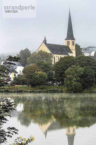 Nebliges Flusstal mit Kirche in bewaldeter Umgebung  die sich im Fluss spiegelt; Krov  Deutschland