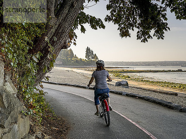 Eine Frau fährt mit dem Fahrrad auf dem Stanley Park Seawall Trail; Vancouver  British Columbia  Kanada