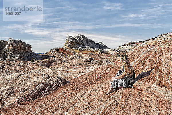 Eine Frau sitzt auf einer Felsformation und genießt die Aussicht bei White Pocket  Vermilion Cliffs National Monument; Kanab  Arizona  Vereinigte Staaten von Amerika