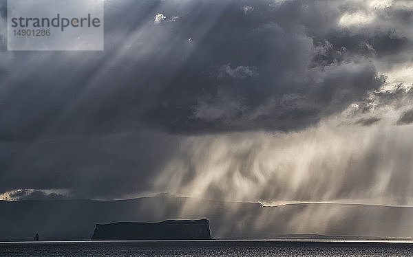 Dramatische Gewitterwolken und Licht über einer Insel vor der Küste Islands; Island