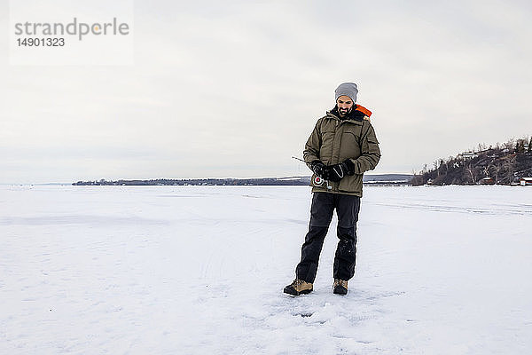 Mann wartet geduldig auf einen Biss beim Eisangeln am Wabamun Lake; Wabamun  Alberta  Kanada