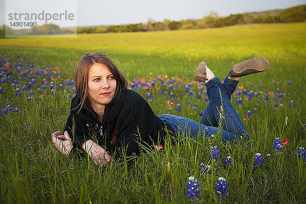 Eine junge Frau liegt in einem Feld mit Bluebonnet-Wildblumen; Waco  Texas  Vereinigte Staaten von Amerika