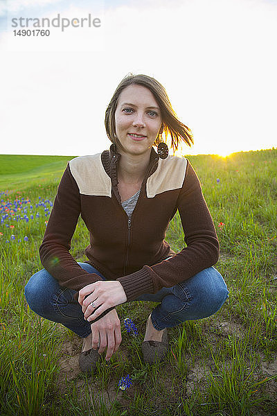 Porträt einer jungen Frau auf einer Wiese mit Wildblumen bei Sonnenuntergang; Waco  Texas  Vereinigte Staaten von Amerika