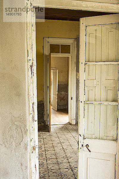 Eine alte  abgenutzte Tür führt in einen leeren Raum mit antikem Keramikfliesenboden; Mendoza  Argentinien