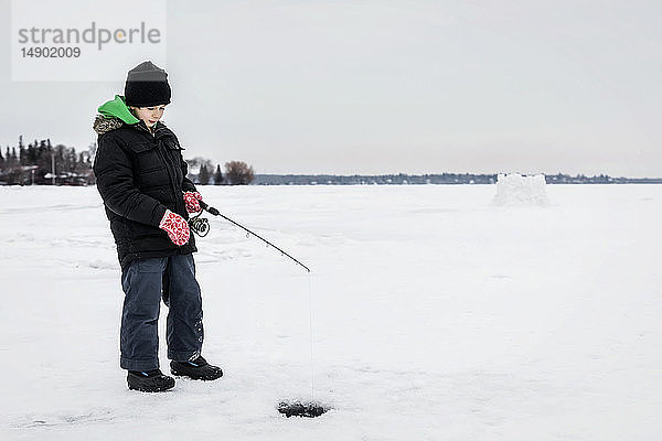Junge wartet geduldig auf einen Biss beim Eisangeln am Wabamun Lake; Wabamun  Alberta  Kanada