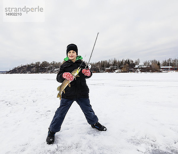 Ein kleiner Junge fängt einen Hecht beim Eisfischen auf dem Wabamum-See während eines Familienausflugs im Winter; Wabamun  Alberta  Kanada