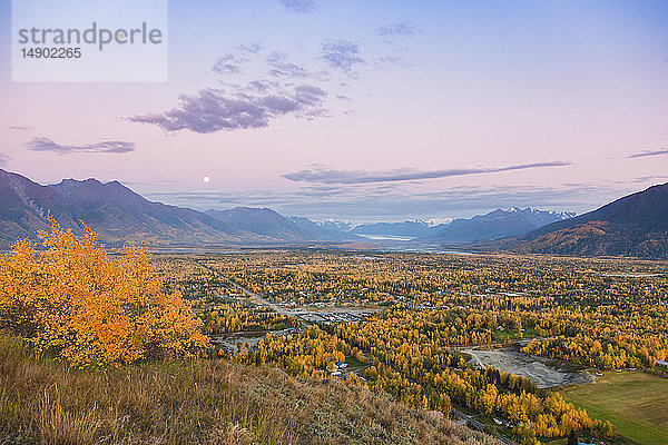 Blick auf den Mond  der über Palmer und dem Knik River von der Butte aus aufgeht  im Hintergrund die Chugach Mountains während der Dämmerung an einem klaren Abend  Süd-Zentral-Alaska; Palmer  Alaska  Vereinigte Staaten von Amerika
