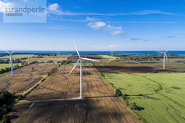 Große Windkraftanlagen auf landwirtschaftlichen Feldern mit einem See im Hintergrund und blauem Himmel mit Wolken  westlich von Port Colborne; Ontario  Kanada