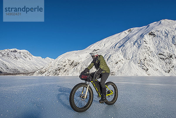 Ein Mann fährt mit seinem Fatbike über den zugefrorenen Portage Lake mitten im Winter in Süd-Zentral-Alaska; Alaska  Vereinigte Staaten von Amerika