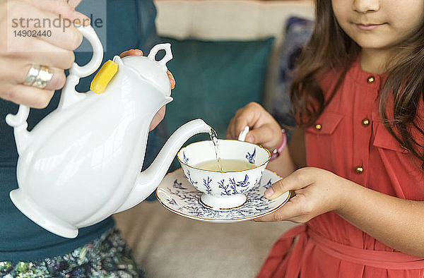 Eine Mutter gießt Tee in eine Teetasse mit Untertasse für ihre Tochter; Surrey  British Columbia  Kanada