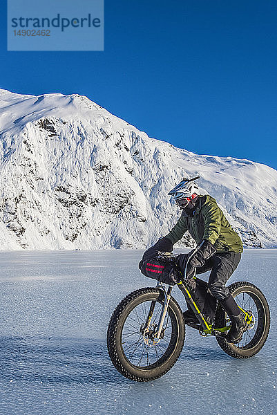 Ein Mann fährt mit seinem Fatbike über den zugefrorenen Portage Lake mitten im Winter in Süd-Zentral-Alaska; Alaska  Vereinigte Staaten von Amerika