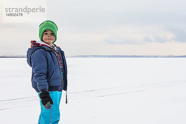 Ein kleiner Junge geht auf einem zugefrorenen See beim Eisfischen während eines winterlichen Familienausflugs spazieren; Wabamun  Alberta  Kanada.