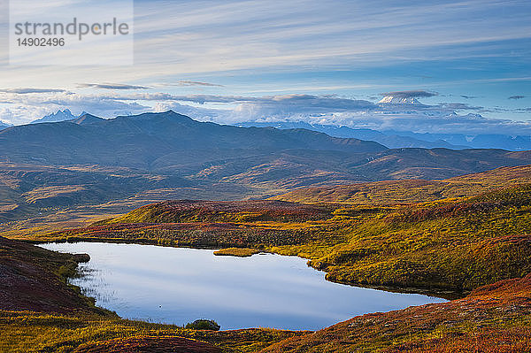 Ein Blick von Peters Hills auf die untergehende Sonne mit sich verziehenden Wolken  die den 20.320' hohen Mount McKinley mit einem unbenannten See im Vordergrund enthüllen; Alaska  Vereinigte Staaten von Amerika