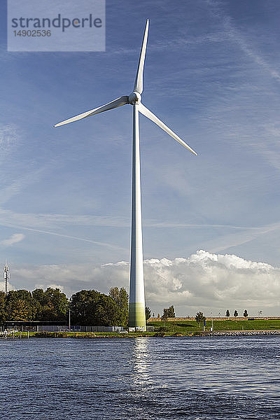 Große Metallwindkraftanlage am Flussufer mit blauem Himmel und Wolken; Spaarndam  Niederlande