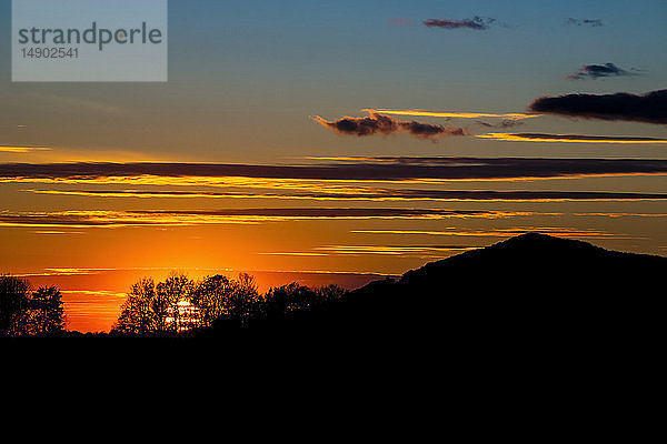 Silhouettierter Hügel und Bäume während eines glühenden Sonnenuntergangs; Waterloo  Quebec  Kanada