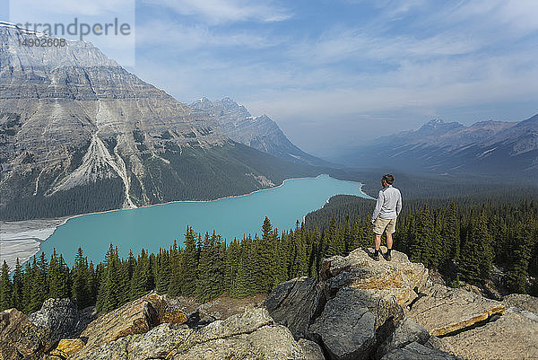 Ein Mann steht auf einem Felsvorsprung mit Blick auf das atemberaubende türkisfarbene Wasser des Peyto Lake im Banff National Park; Alberta  Kanada