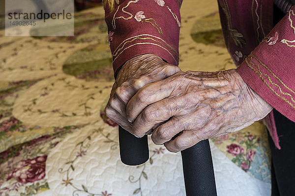Ältere Frau hält sich mit den Händen an einem Stock fest; Olympia  Washington  Vereinigte Staaten von Amerika