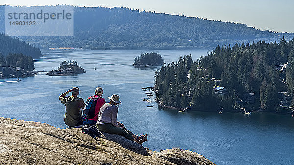 Wanderer sitzen am Quarry Rock auf dem Baden-Powell Trail und blicken auf die Küste  Deep Cove  North Vancouver; Vancouver  British Columbia  Kanada