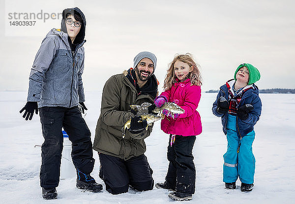 Vater und vier Kinder zeigen ihren Fang  bevor sie ihn beim Eisfischen am Lake Wabamun freilassen; Wabamun  Alberta  Kanada