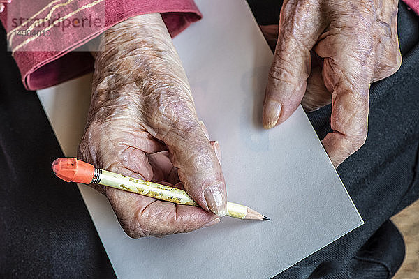Die Hände einer älteren Frau machen sich bereit  eine Notiz mit einem Bleistift zu schreiben; Olympia  Washington  Vereinigte Staaten von Amerika