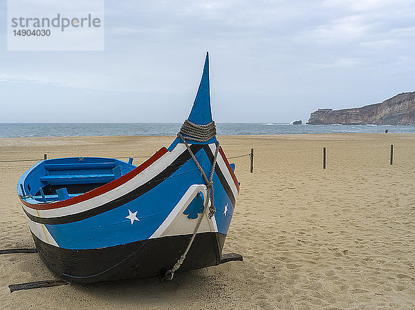 Ein buntes  hölzernes Ruderboot am Strand des Badeortes Nazare; Nazare  Bezirk Leiria  Portugal