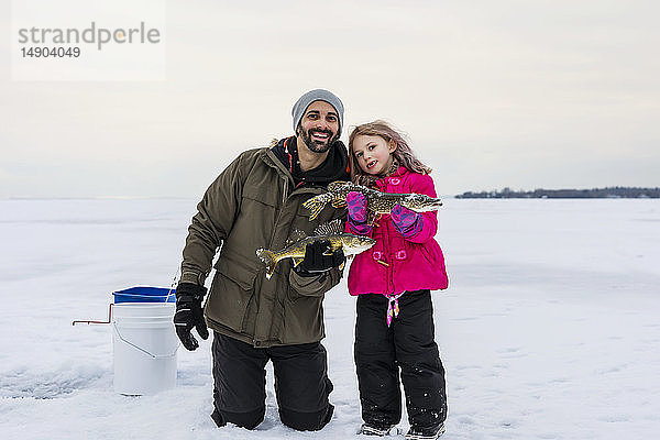 Vater und junge Tochter zeigen ihren Fang  bevor sie ihn beim Eisfischen am Lake Wabamun freilassen; Wabamun  Alberta  Kanada