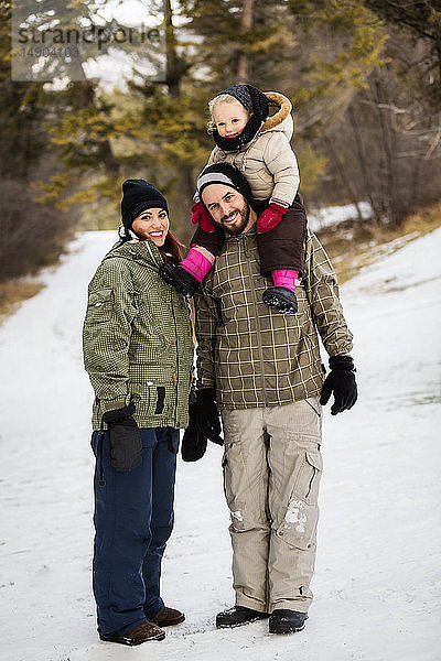 Eine junge Familie wandert mit ihrer kleinen Tochter während eines Familienausflugs im Winter im Freien: Fairmont  British Columbia  Kanada