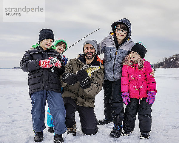 Vater und vier Kinder zeigen ihren Fang  bevor sie ihn beim Eisfischen am Lake Wabamun freilassen; Wabamun  Alberta  Kanada