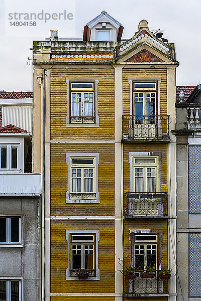 Fassade eines hohen Wohngebäudes aus gelbem Backstein mit kleinen Balkonen und Fenstern; Lissabon  Region Lisboa  Portugal