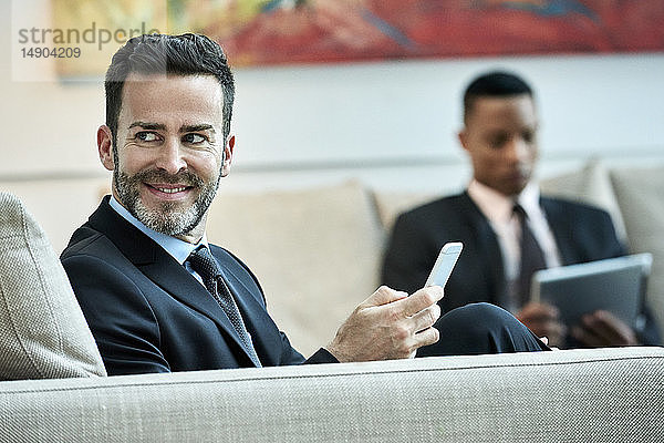 Geschäftsmann benutzt Smartphone in der Hotellobby
