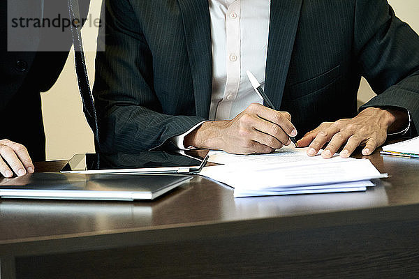 Geschäftsmann beim Unterzeichnen eines Dokuments im Büro