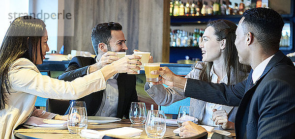Geschäftsleute stoßen in einer Bar auf ein Getränk an