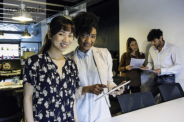 Lächelnde Geschäftsfrauen mit digitalem Tablet im Büro