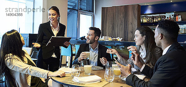 Kellnerin nimmt Bestellungen von Geschäftsleuten in einer Bar auf