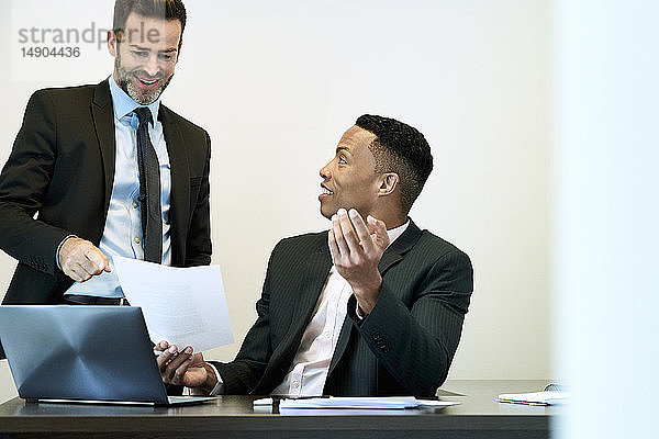 Geschäftsleute diskutieren über ein Dokument am Schreibtisch im Büro