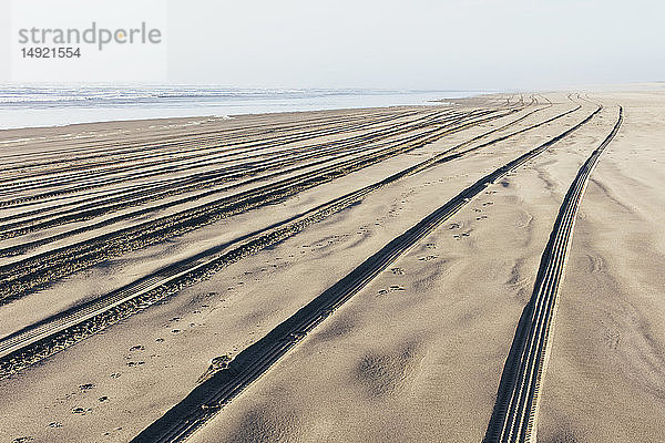 Reifenspuren auf der weichen Sandoberfläche eines Strandes.