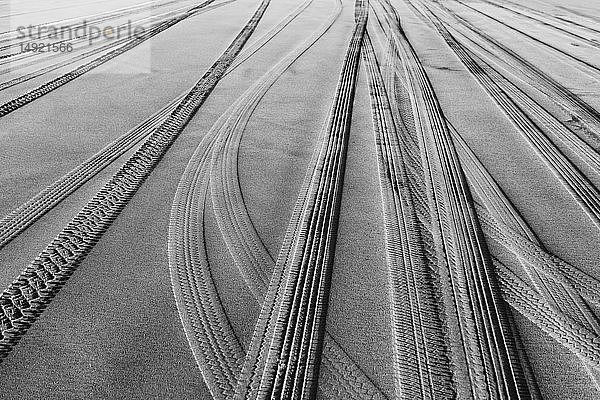 Reifenspuren auf der weichen Sandoberfläche eines Strandes.