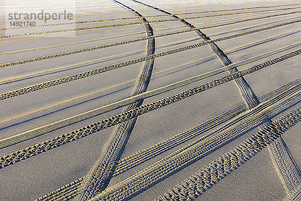 Reifenspuren auf der weichen Sandoberfläche eines Strandes.