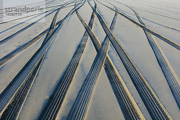 Reifenspuren auf der weichen Sandoberfläche eines Strandes.