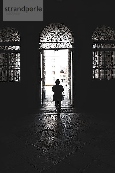 Silhouette einer Frau  die durch eine gewölbte Tür in Venedig  Venetien  Italien  geht.