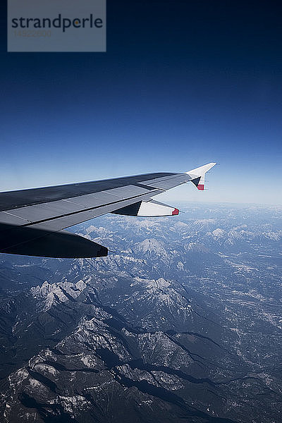 Blick über die Alpen aus dem Fenster eines Passagierflugzeugs.