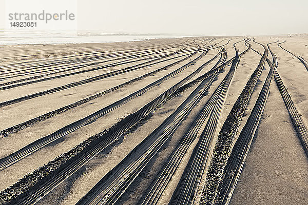 Reifenspuren auf der weichen Sandoberfläche eines Strandes.