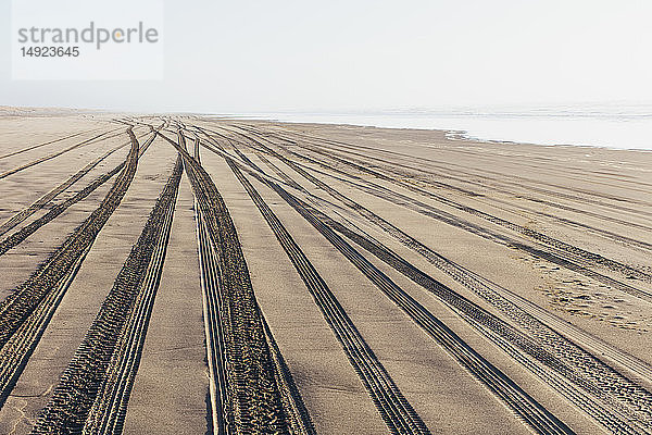 Reifenspuren auf der weichen Sandoberfläche eines Strandes.