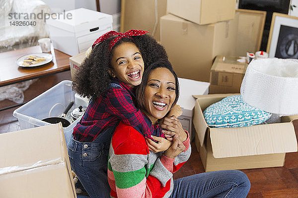 Porträt glückliche  begeisterte Mutter und Tochter  die sich zwischen Kisten umarmen  Umzug