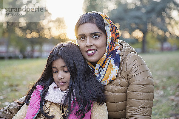 Porträt lächelnde Mutter in Hijab sitzt im Herbst Park mit Tochter