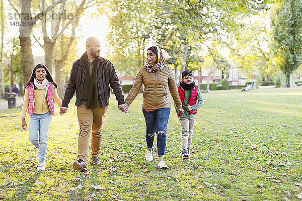 Muslimische Familie hält sich an den Händen  Spaziergang im sonnigen Herbstpark