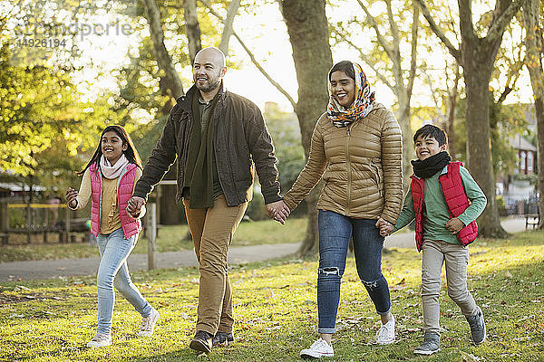 Muslimische Familie hält sich an den Händen  Spaziergang im Herbstpark