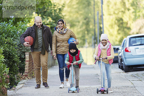 Muslimische Familie beobachtet und fährt Roller auf dem Bürgersteig