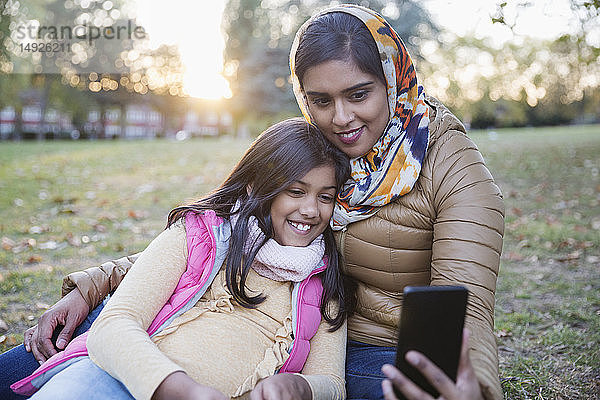 Muslimische Mutter im Hidschab macht Selfie mit Tochter im Herbstpark