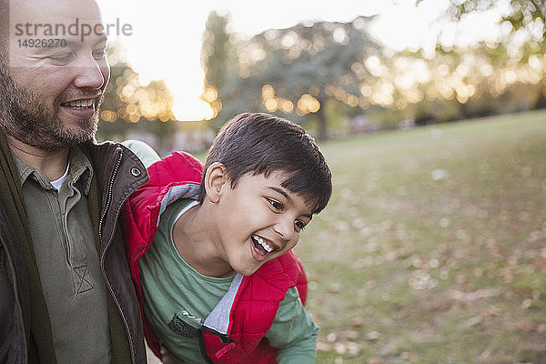 Glücklicher Vater und Sohn spielen im Herbst im Park